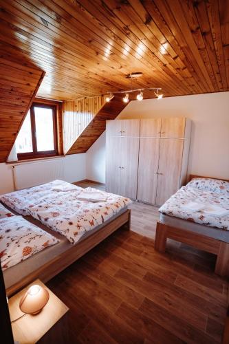 a bedroom with two beds and a wooden ceiling at Apartmány s výhledem in Horní Maršov