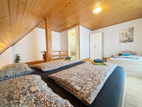 two beds in a room with wooden ceilings at Apartments Rupnik in Bovec