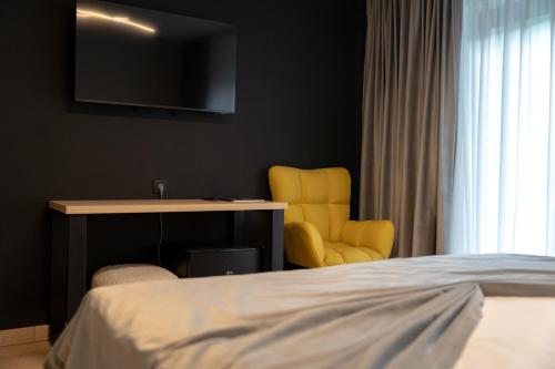 a bedroom with a bed and a desk and a yellow chair at Piscul Negru Hotel - Transfagarasan in Cumpăna