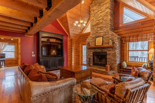 a living room with leather furniture and a stone fireplace at The Feisty Fox in Sugar Mountain