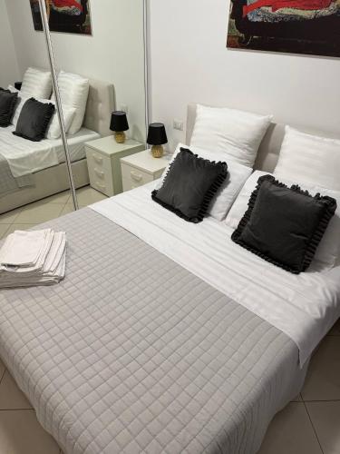 a large white bed with black pillows in a room at Appartamento ELDORADO in Lido di Pomposa