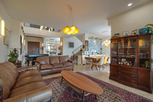 a living room with leather furniture and a dining room at Villa Netofa (Kosher) in Mitspe Netofa