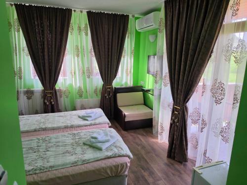 a green bedroom with two beds and a chair at Къща за гости Торлашка среща in Vŭrbovo