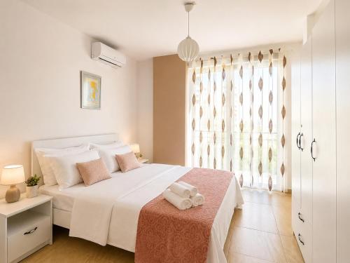 a white bedroom with a large white bed and a window at Sea View Marjana Apartment in Skataj