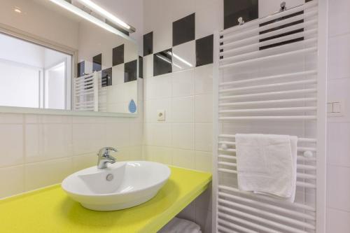 a white bathroom with a sink and a mirror at Résidence Odalys Le Château de Kéravéon in Erdeven