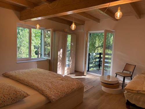 a bedroom with a bed and windows and a chair at Fűzfás Apartman in Siófok