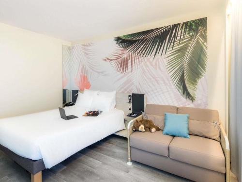 a bedroom with a couch and a palm tree mural at Novotel Monte-Carlo in Monte Carlo