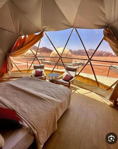 a bedroom with a bed and a view of the desert at Desert Hello Camp in Wadi Rum