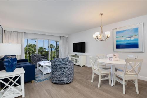 a living room with a blue couch and a table and chairs at Beach Villa 2323 - Captiva One Bedroom Deluxe Beachfront Residence in Captiva