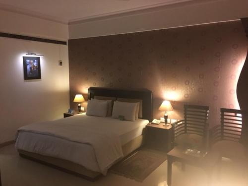 a bedroom with a bed and two tables and two lamps at Shiva Oasis Resort in Neemrana