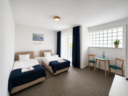 a bedroom with two beds and a table and a window at Apartamenty Na Fali in Jastarnia