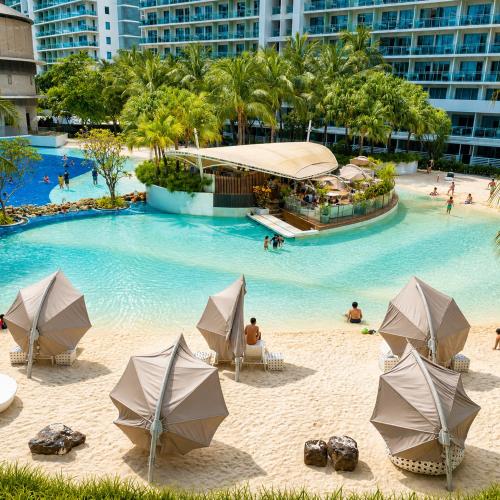 a swimming pool with umbrellas and people on a beach at Azure Urban Resort Residences by Value Suites in Manila