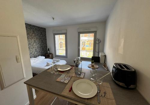 a room with a table with plates and glasses on it at Studio Quartier Amiens in Amiens