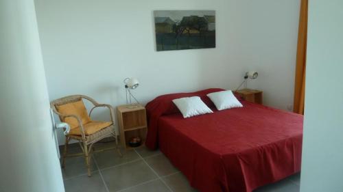 a bedroom with a red bed and a chair at La Roseraie des Côtes - Piscine in Vinsobres