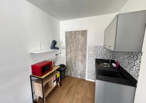 a kitchen with a refrigerator and a red microwave at Studio Quartier Amiens in Amiens