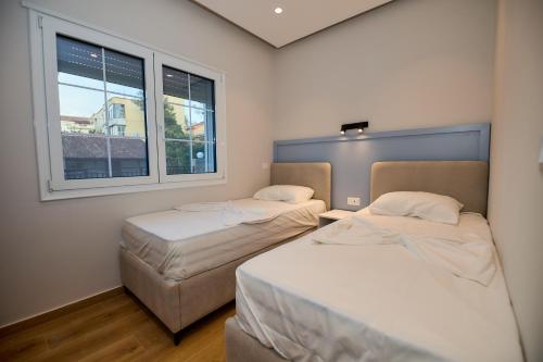 two beds in a room with two windows at Blue Golem Durres Albania in Golem