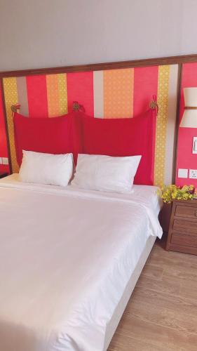 a bedroom with a white bed with a red headboard at APEC Mandala Mũi Né Official - Diễm Phạm Travel in Phan Thiet