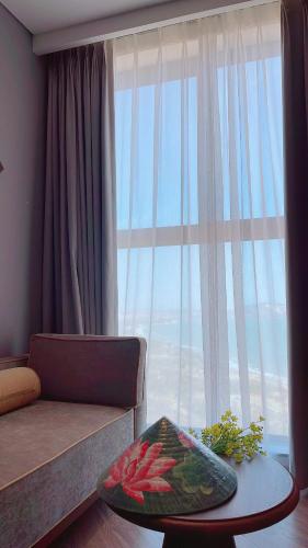 a living room with a couch and a large window at APEC Mandala Mũi Né Official - Diễm Phạm Travel in Phan Thiet