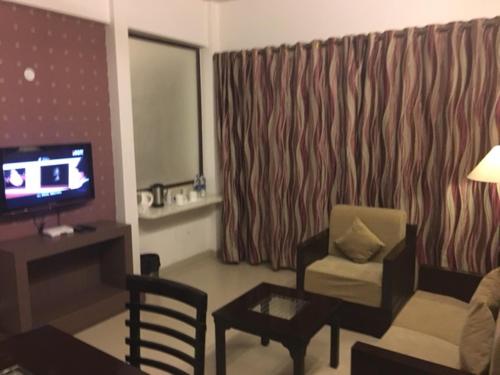 a living room with a couch and a chair and a television at Shiva Oasis Resort in Neemrana