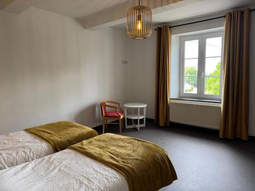 a bedroom with a bed and a window and a chair at Chez Marraine in Nassogne