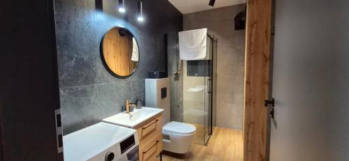 a bathroom with a sink and a toilet and a mirror at Apartament Baltic 13 Mielno in Mielno