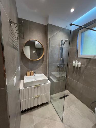 a bathroom with a sink and a mirror and a shower at Drymades Studio Apartment in Gjilek
