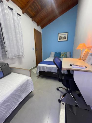 a bedroom with two beds and a desk with a computer at Hostel Recanto Verde - Conforto e Tranquilidade em Campo Grande in Campo Grande