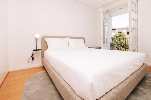a large white bed in a room with a window at Micah's Biscainhos Apartment by Quantique in Braga