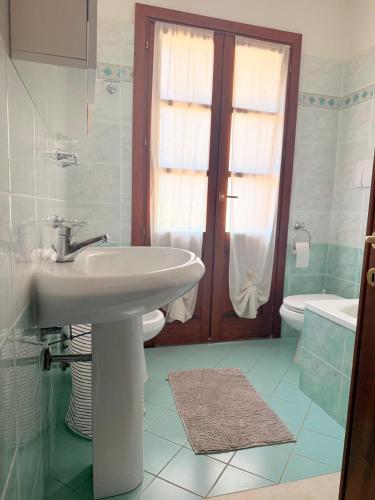 a white bathroom with a sink and a toilet at Al porto in Àrbatax