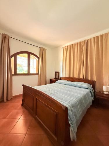 a bedroom with a bed and a window with curtains at Al porto in Àrbatax