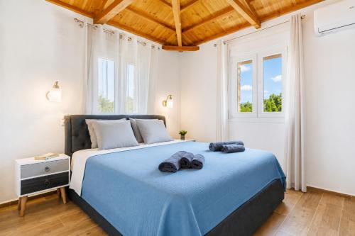 a bedroom with a blue bed with two towels on it at Oak Tree Cottage in Pefkias
