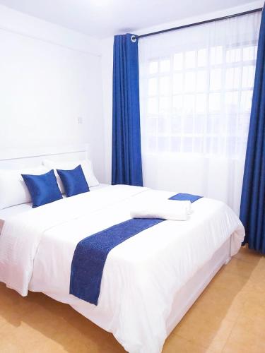 a bedroom with a large bed with blue curtains at Nest homes in Eldoret