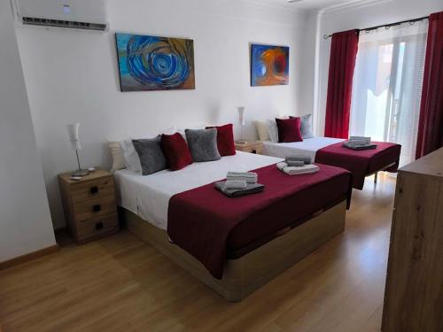 a bedroom with two beds with red pillows at Santa Rita Guest House in Olhão