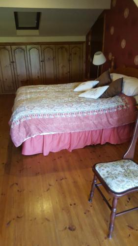 a bedroom with a bed and a chair and a lamp at Tulla Villa Self Catering in Riverstown