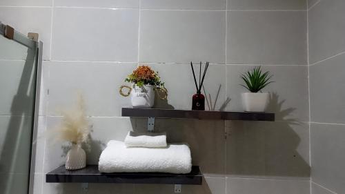 a bathroom with a shelf with towels and plants at Olivewood Apartments in Ankuru