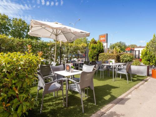 a group of tables and chairs with an umbrella at Ibis Madrid Alcorcon Tresaguas in Alcorcón