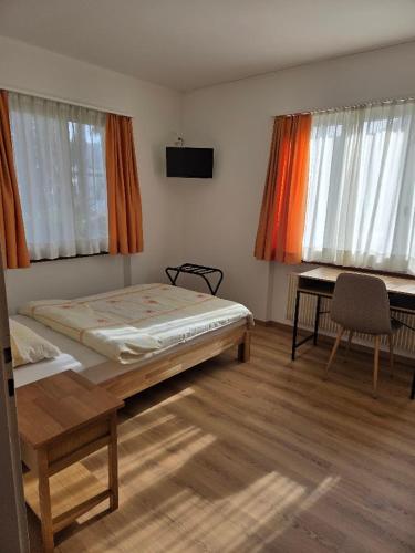 a bedroom with a bed and a desk and two windows at Garni Molinazzo in Agno
