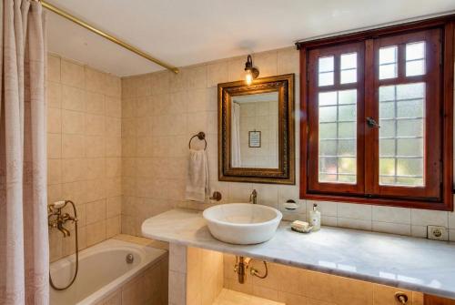 a bathroom with a sink and a tub and a mirror at Elounda Almond Tree Villa Private Pool, Sea Views & Birds in a Relaxing Authentic Cretan Escape in Vrouchas