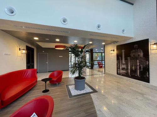 a lobby with red chairs and a potted plant at Ibis Roma Fiera in Rome