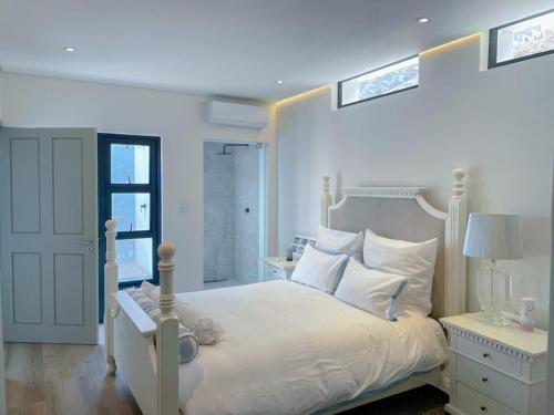 a white bedroom with a white bed and a window at Suite 10 in Windhoek