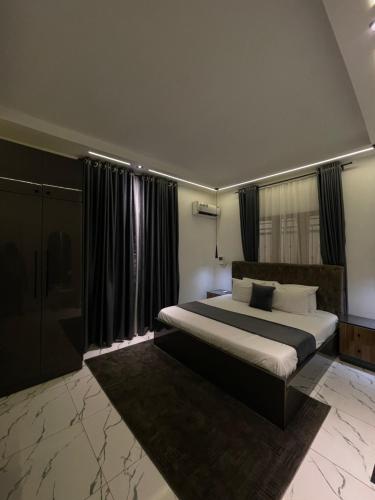 a bedroom with a large bed with black curtains at Olivewood Apartments in Ankuru