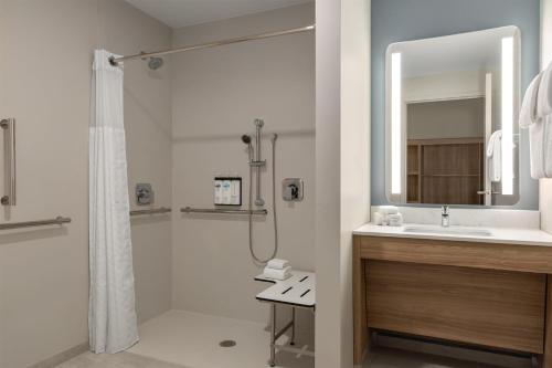 a bathroom with a shower and a sink and a mirror at Hyatt Studios Harrisonburg in Harrisonburg