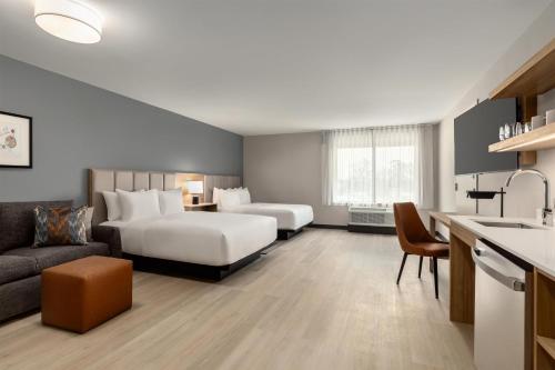 a hotel room with two beds and a couch at Hyatt Studios Harrisonburg in Harrisonburg