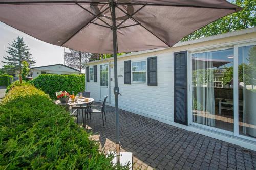a patio with a table and an umbrella at 80, Midden in de natuur - Airco! in Oisterwijk
