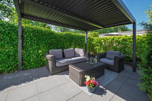 acovered patio with two chairs and a table with flowers at 80, Midden in de natuur - Airco! in Oisterwijk
