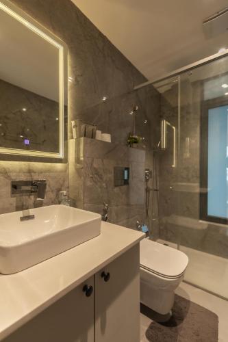 a bathroom with a sink and a toilet and a mirror at SOLARIS APARTMENT-Sky Suites in Accra