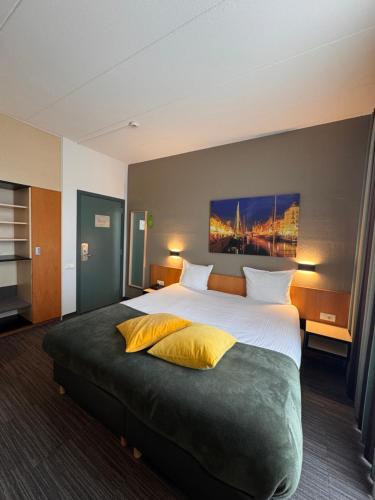 a hotel room with a large bed with yellow pillows at Hobbit Hotel Brussels Airport Zaventem in Zaventem