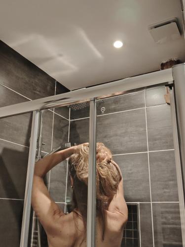 a woman standing in a shower in a bathroom at Le Paddock - Chambres et table d'hôtes in Le Déluge