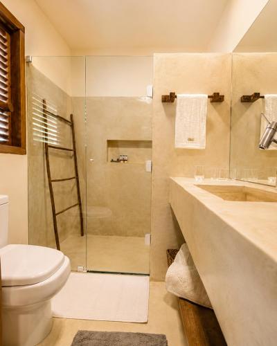 a bathroom with a shower and a toilet and a sink at Pousada Awêry Caraíva in Caraíva