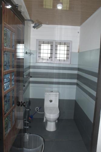 a bathroom with a toilet and a glass shower at Mist Farm Resort in Avanāshi